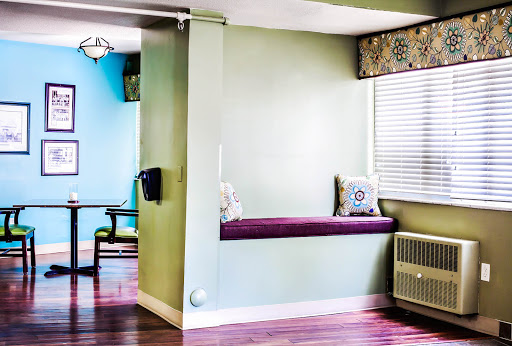 A cozy corner of a modern interior featuring colorful walls and a comfortable window seat.