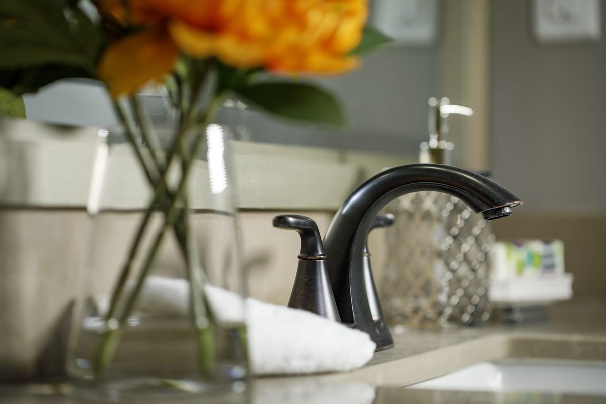 A close-up of a bathroom sink with a stylish faucet and decorative flowers.