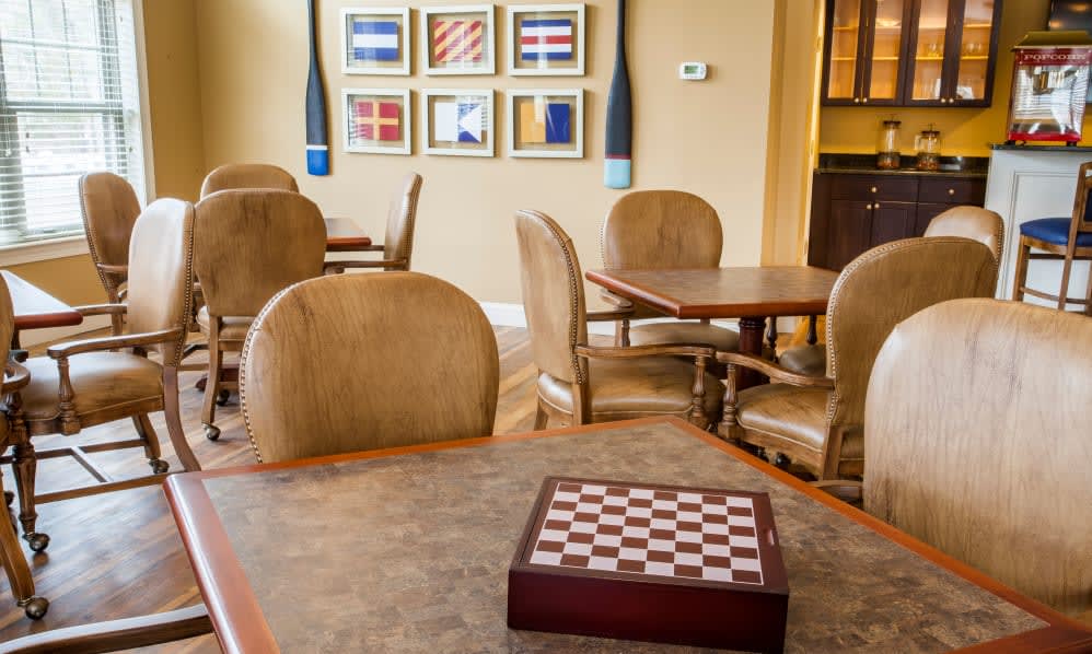 A cozy game room with a chess board on the table and comfortable seating, adorned with colorful artwork on the walls.