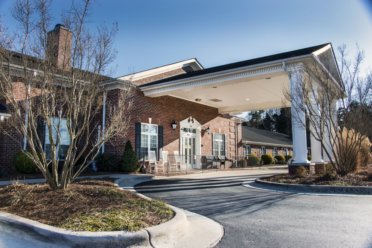 A well-maintained building entrance with a driveway and landscaped surroundings under a clear sky.