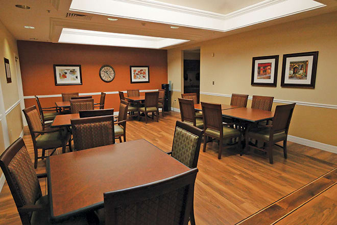 A modern meeting room with tables and chairs arranged neatly.