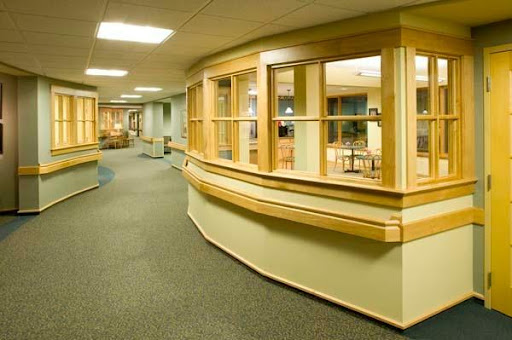 A modern hospital corridor featuring wooden accents and ample lighting.