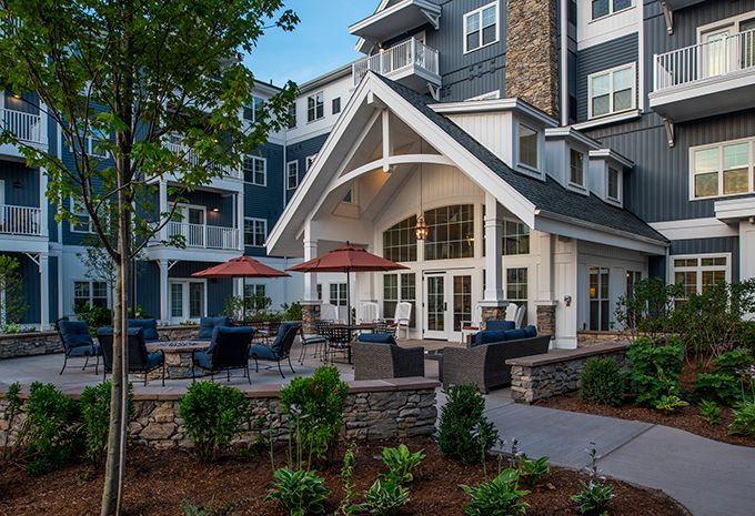 A modern apartment building with a landscaped patio and outdoor seating area.