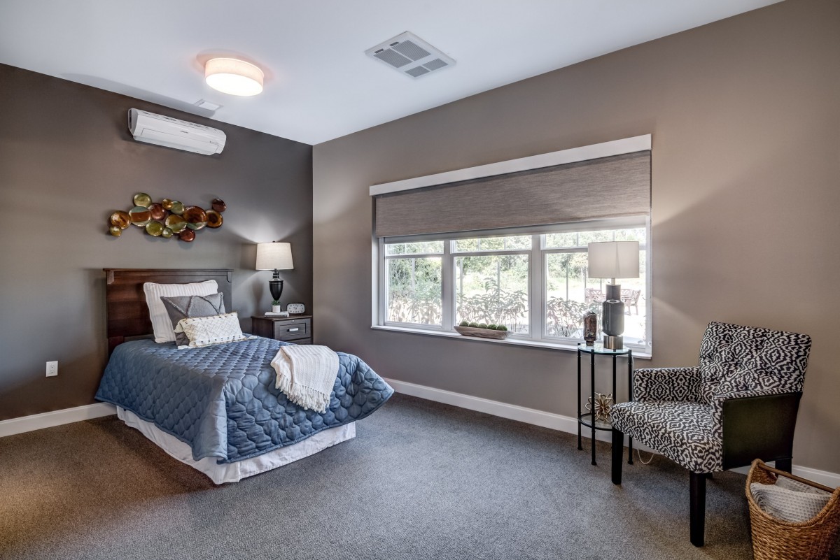 A modern bedroom with a single bed, large window, and stylish decor.