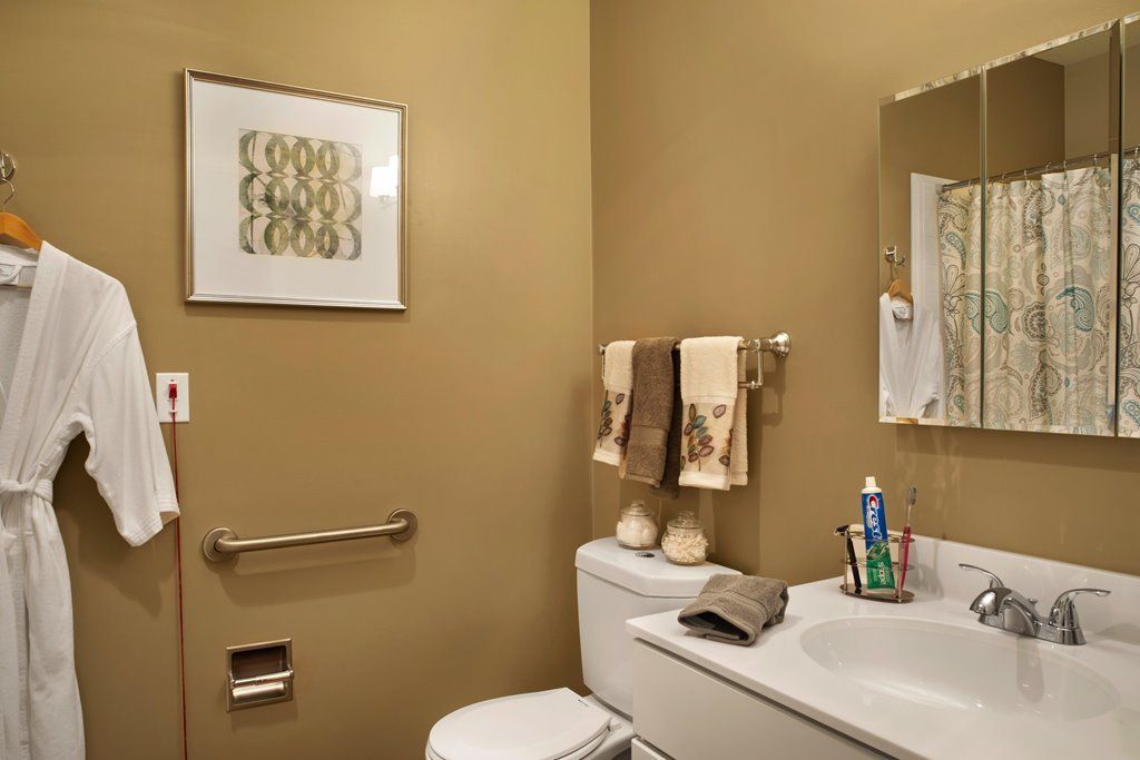 A cozy bathroom with warm-toned walls, featuring a toilet and sink adorned with towels and decor.
