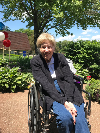 A joyful senior woman enjoying a sunny day in the garden, sitting in her wheelchair.
