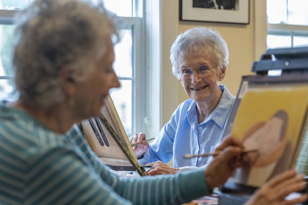 Two older adults enjoying a painting session in an art class.