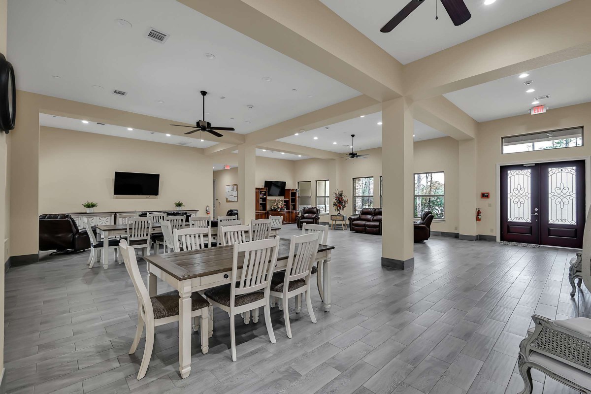 A spacious and well-lit community dining area with modern furnishings and a television.