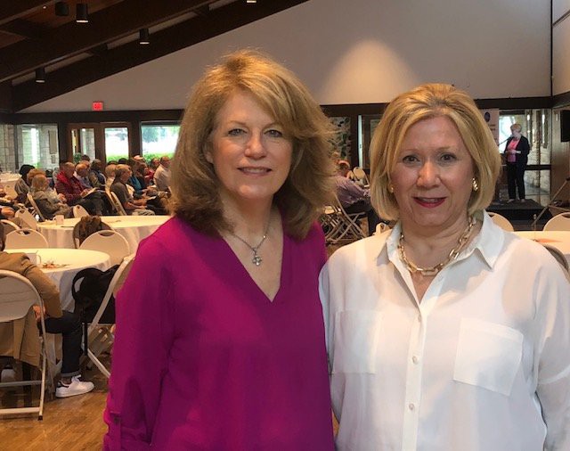 Two women posing for a photo at an indoor event.