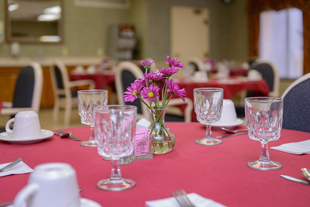 A beautifully set dining table with crystal glasses and a vase of flowers in a restaurant.