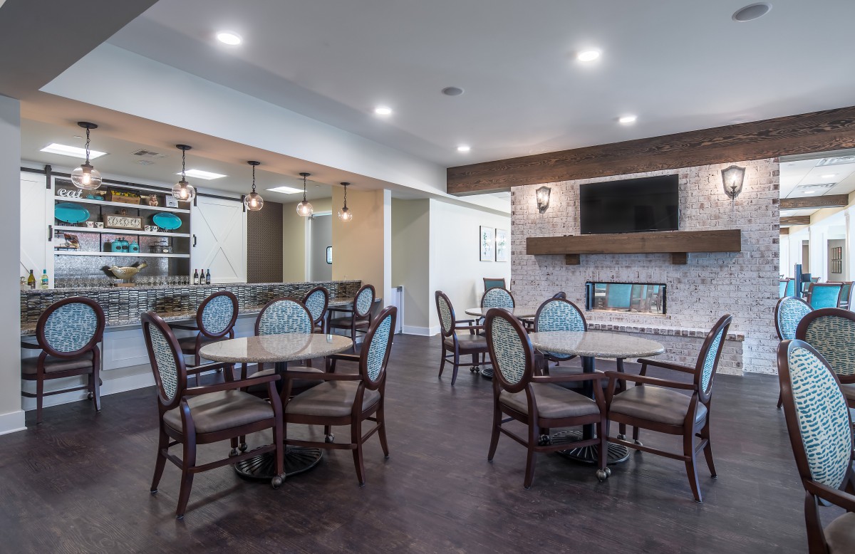 A modern dining area featuring several tables and chairs, a fireplace, and a wall-mounted television.