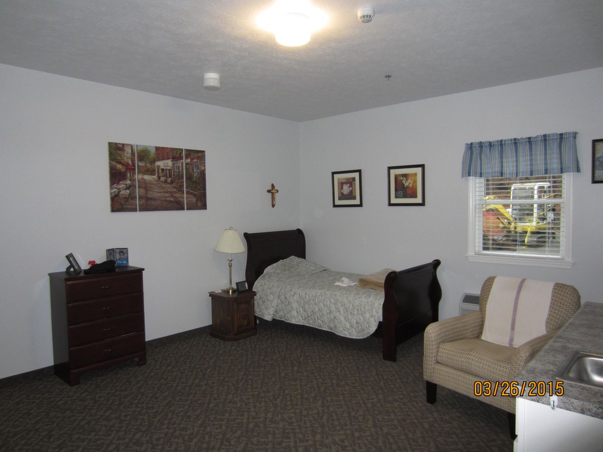 A cozy bedroom with a single bed, dresser, and framed wall art.