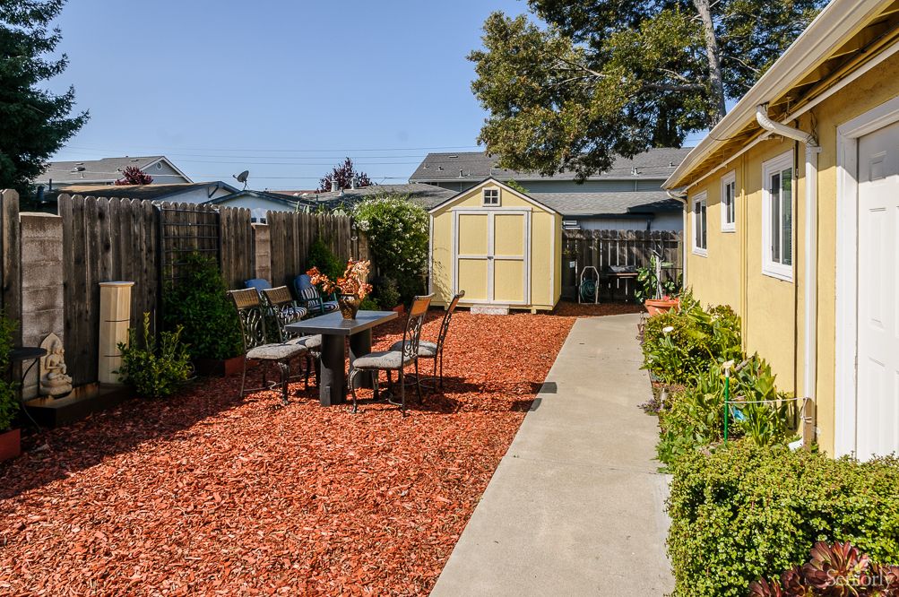 A well-maintained backyard with a shed, outdoor seating area, and landscaped garden.