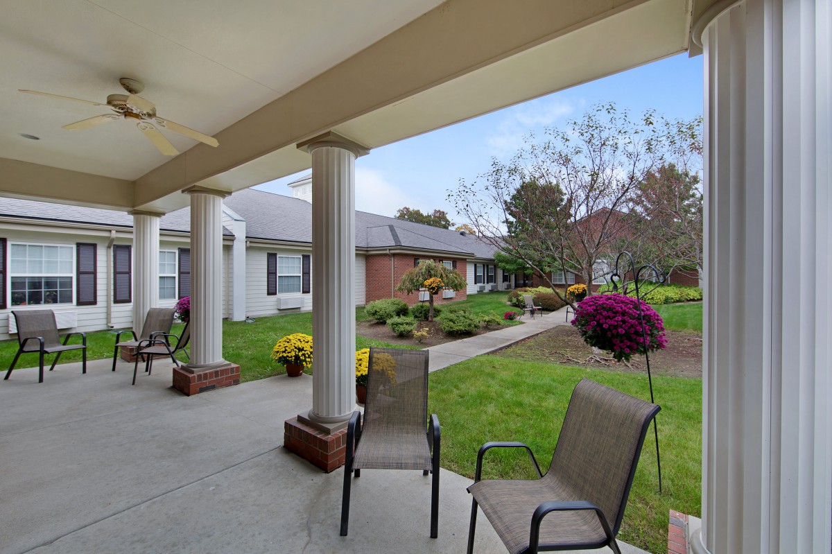 A covered patio with chairs overlooking a landscaped garden.