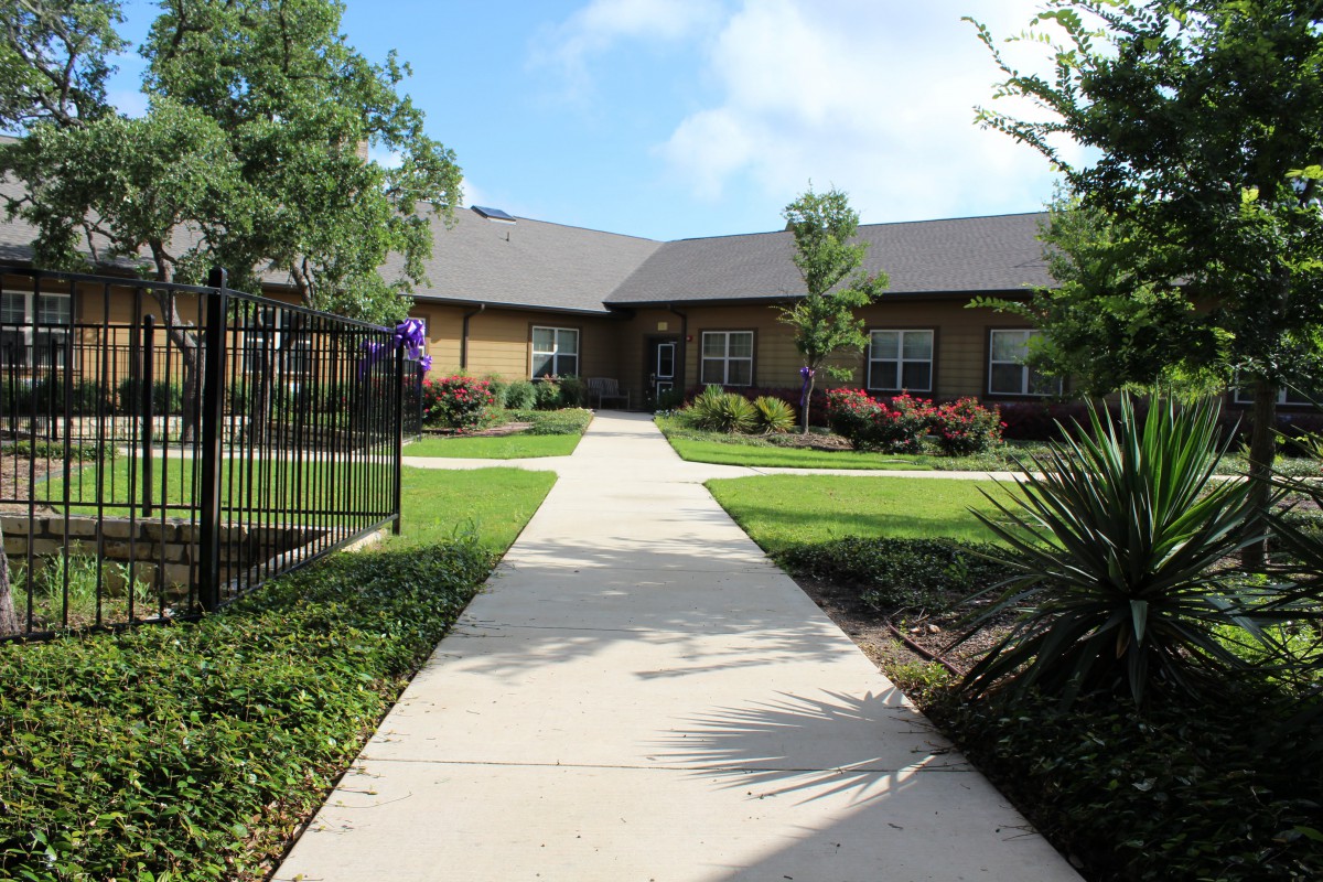 A well-maintained garden with a concrete pathway leading to a residential building.