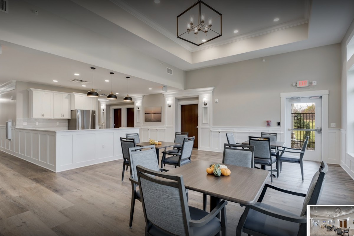 A modern dining area with tables and chairs, adjacent to a kitchen space.