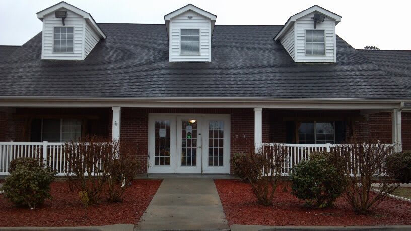 A brick house with a porch and multiple windows.