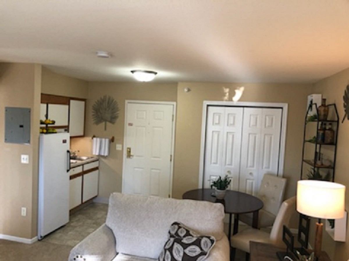 A cozy apartment interior featuring a small living area with a kitchenette and seating.