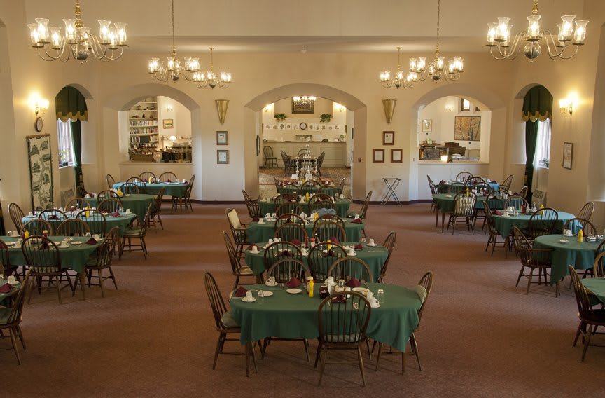 A spacious dining area with neatly arranged tables and elegant chandeliers.