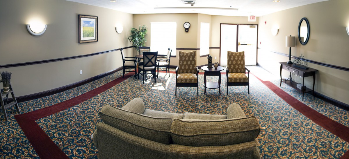 A cozy living room with a sofa, chairs, and a small table arranged on a patterned carpet.