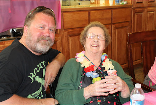 A joyful moment shared between a man and an elderly woman, both enjoying a celebration.