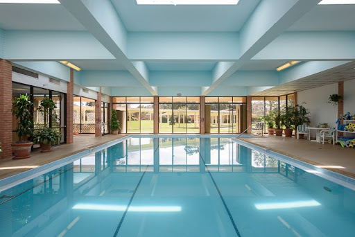 A serene indoor swimming pool, featuring large windows and bright blue walls that create a tranquil atmosphere.