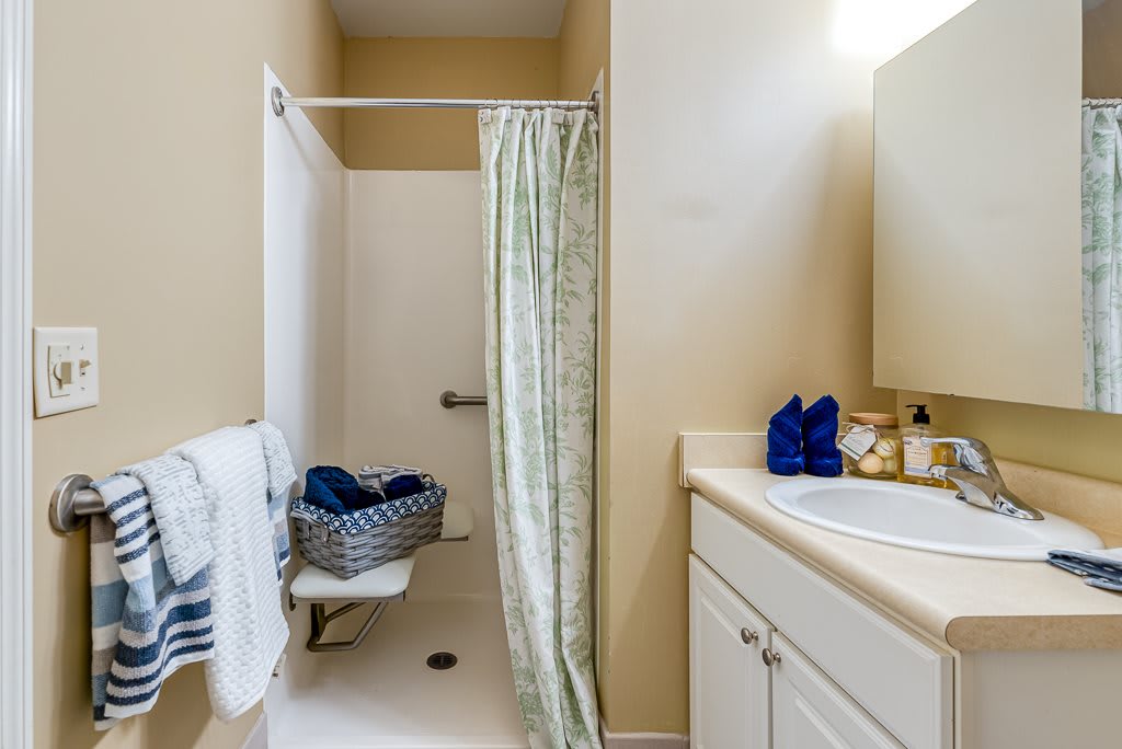 A neatly organized bathroom with a shower curtain, sink, and towels.