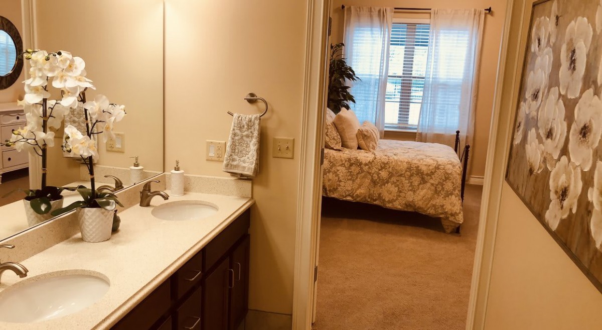 View of a cozy bedroom through a bathroom entrance.