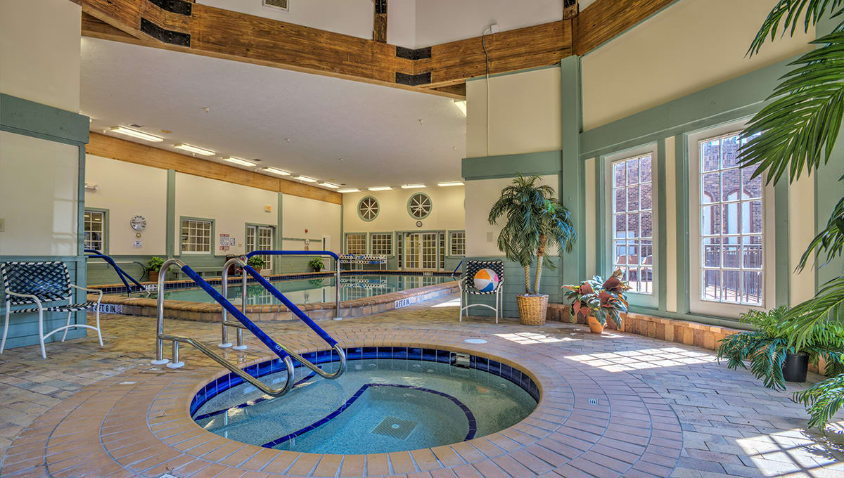 An inviting indoor recreation area featuring a hot tub and swimming pool, complete with cozy seating and natural lighting.