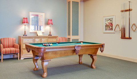A game room featuring a wooden pool table with a green top and decorative elements.
