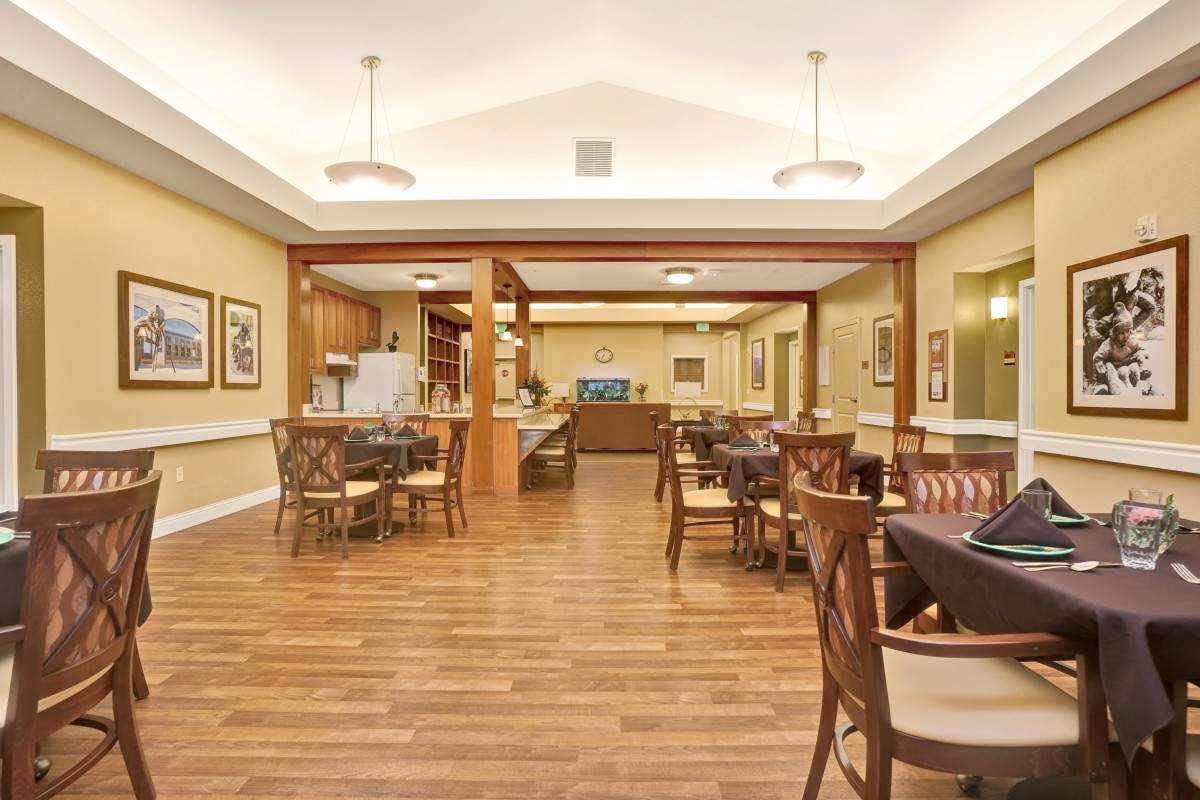 A spacious dining area with neatly arranged tables and chairs, featuring a hardwood floor and modern lighting.