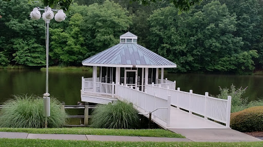 A serene gazebo situated by a tranquil pond, surrounded by lush greenery.