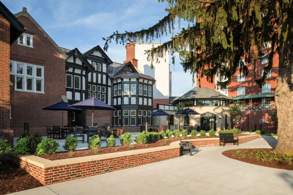 A Tudor-style building with outdoor seating and a garden area on a sunny day.