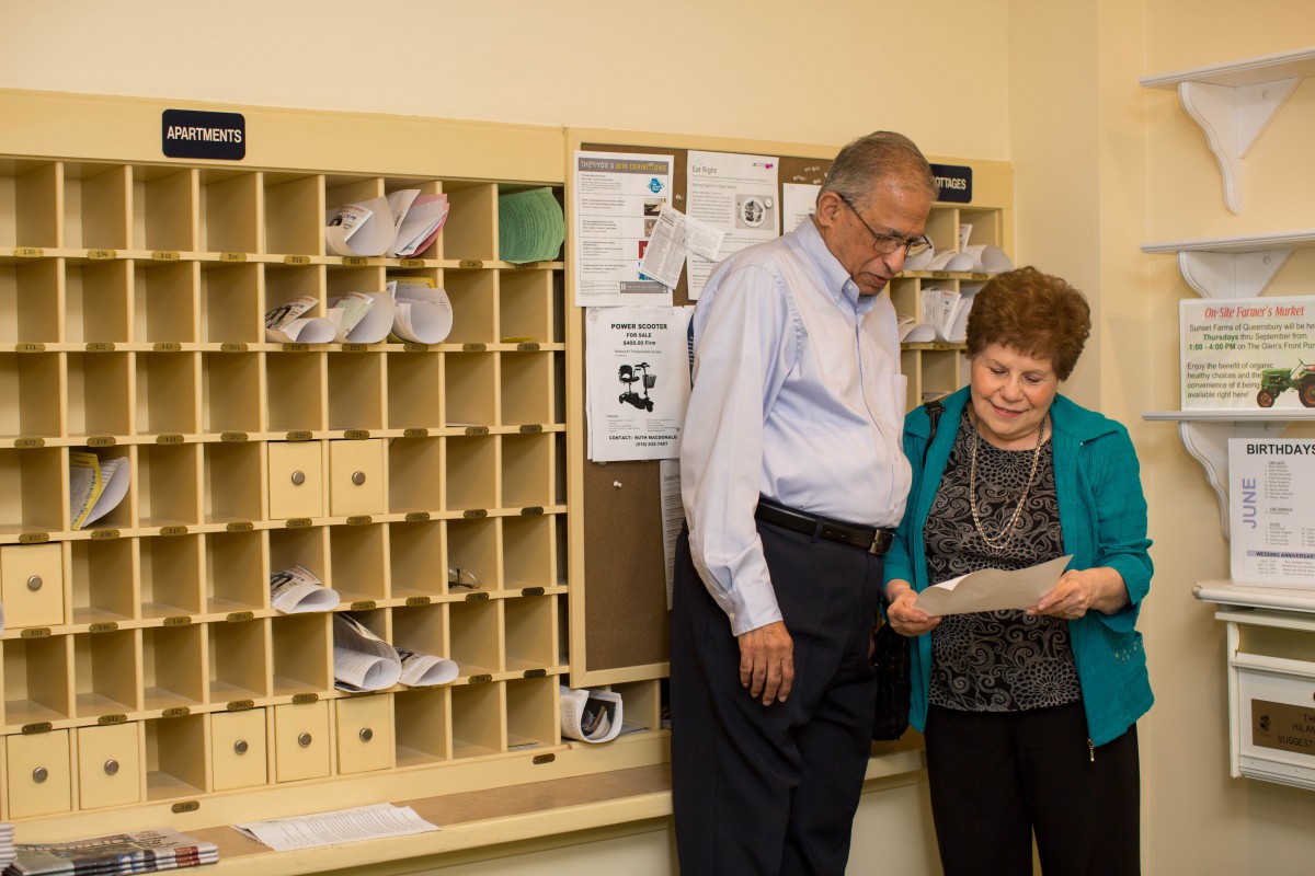 Two individuals review a document in an office mailroom.