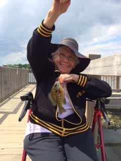 Person smiling while holding a fish on a dock.