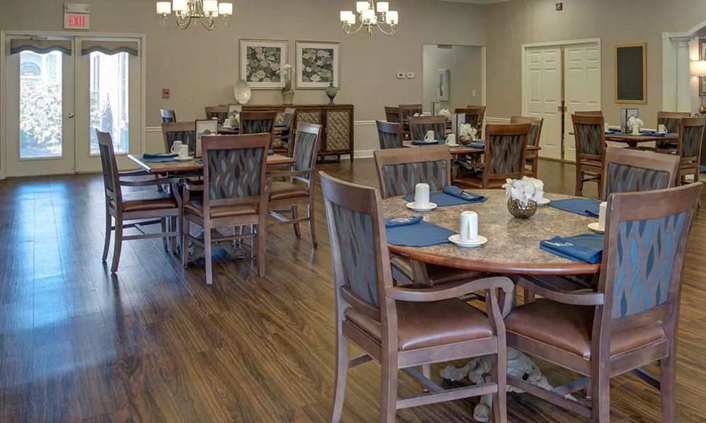 A spacious dining area with multiple tables and chairs on a wooden floor.