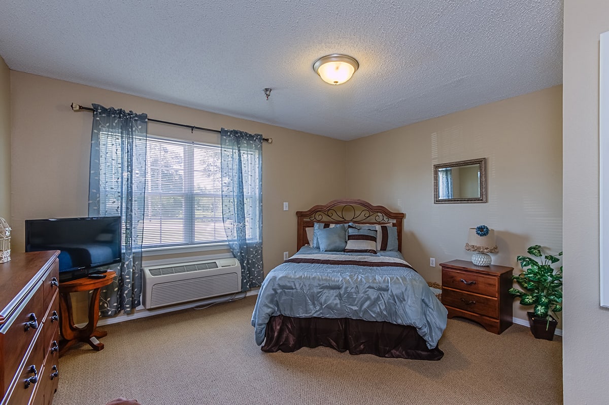 A cozy bedroom with a bed, nightstands, and a large window.