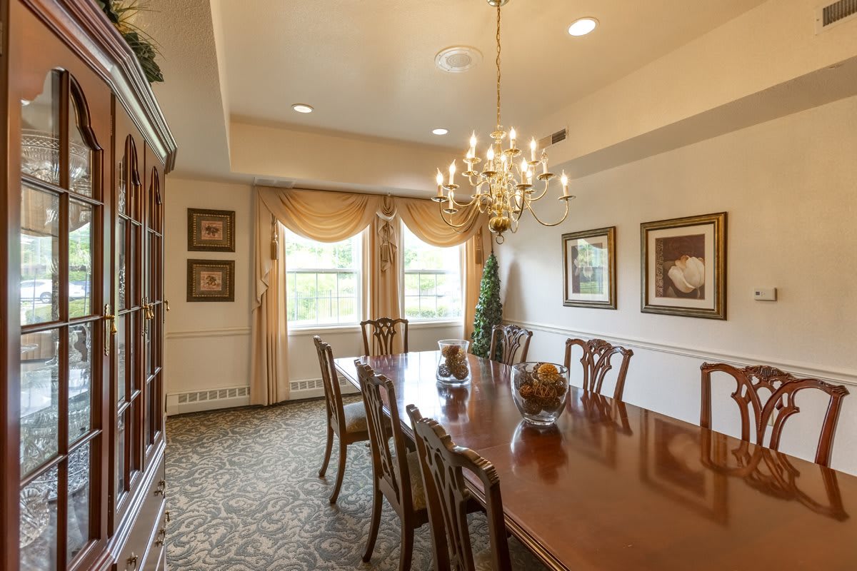 An elegant dining room featuring a long wooden table, ornate chairs, and a chandelier.