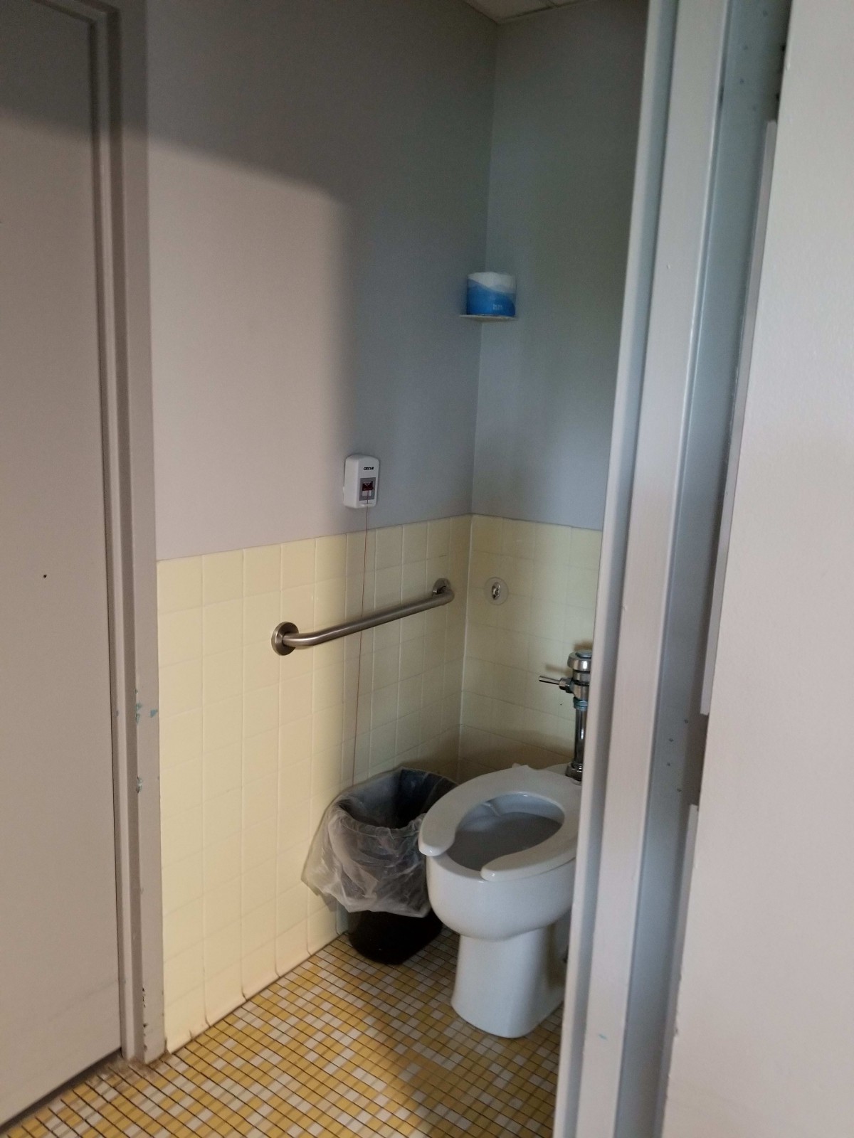 A small bathroom with a toilet and trash can.
