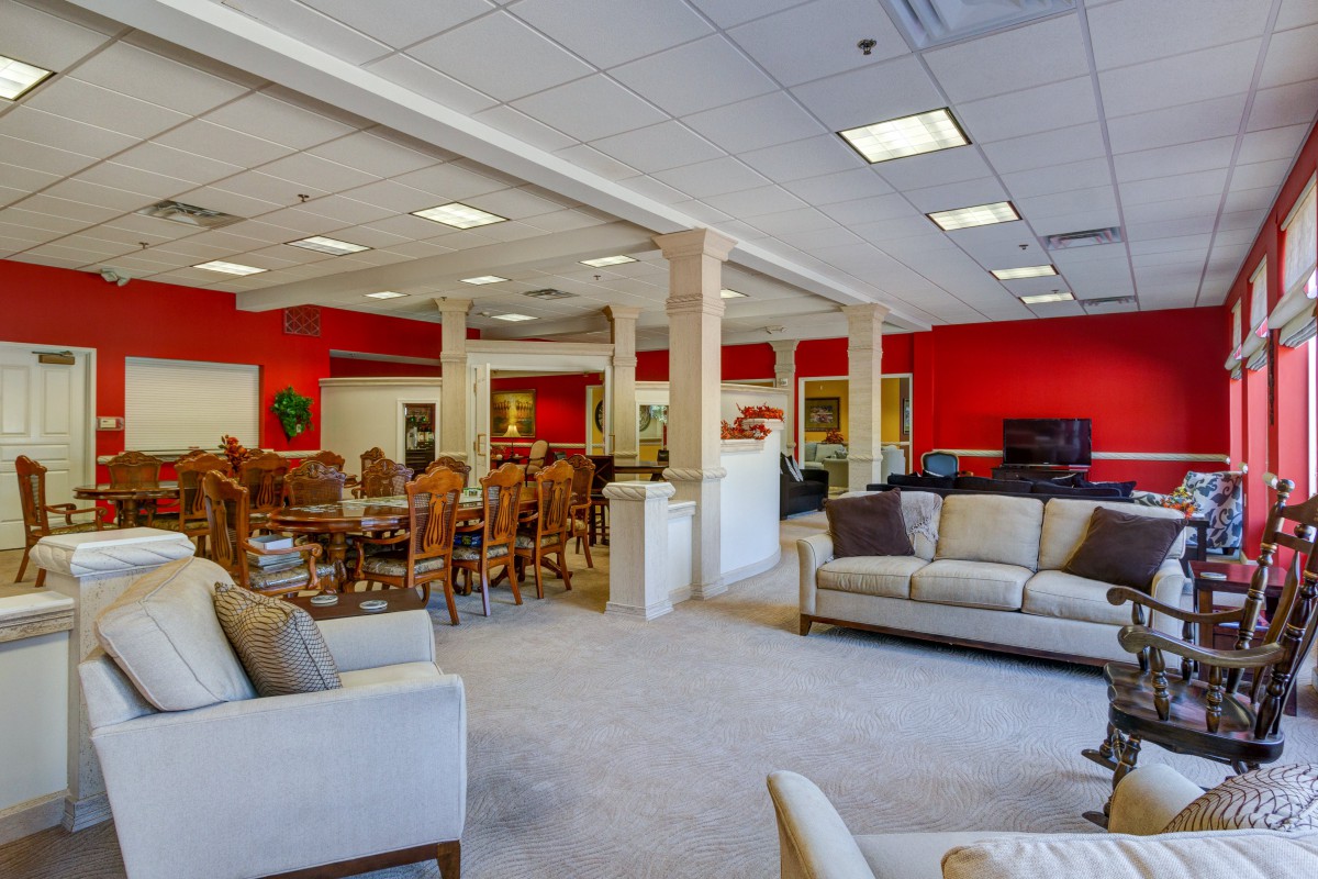 A spacious lounge area with red walls, featuring comfortable sofas and dining tables.