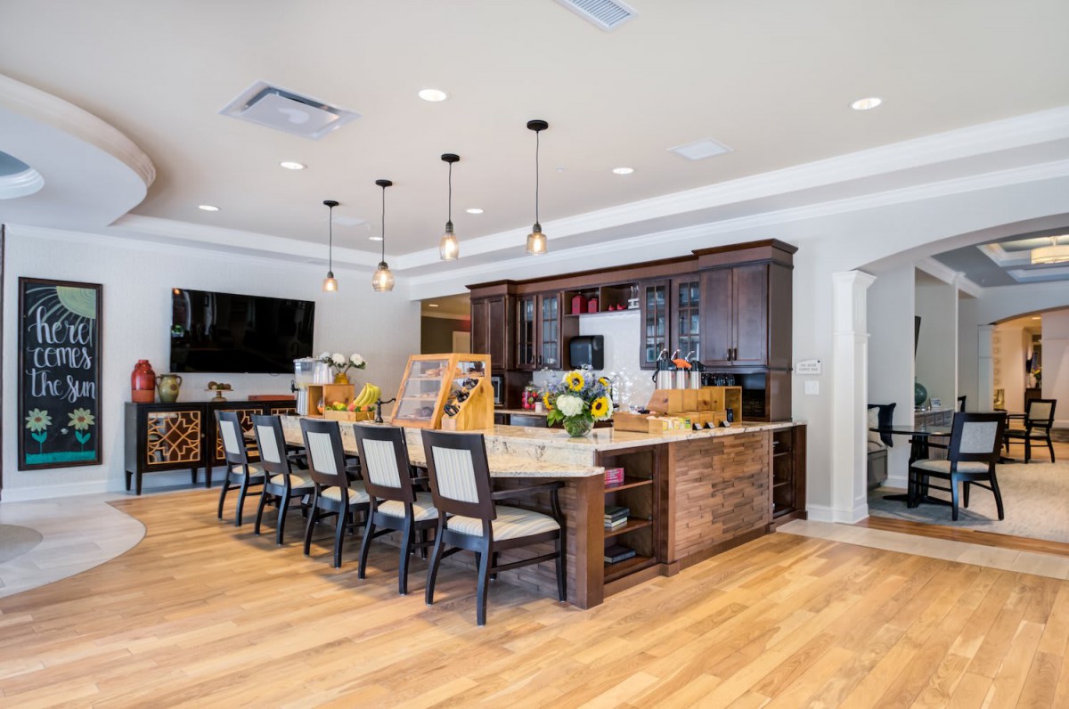 A modern kitchen with a large island and seating area, featuring pendant lighting and hardwood flooring.