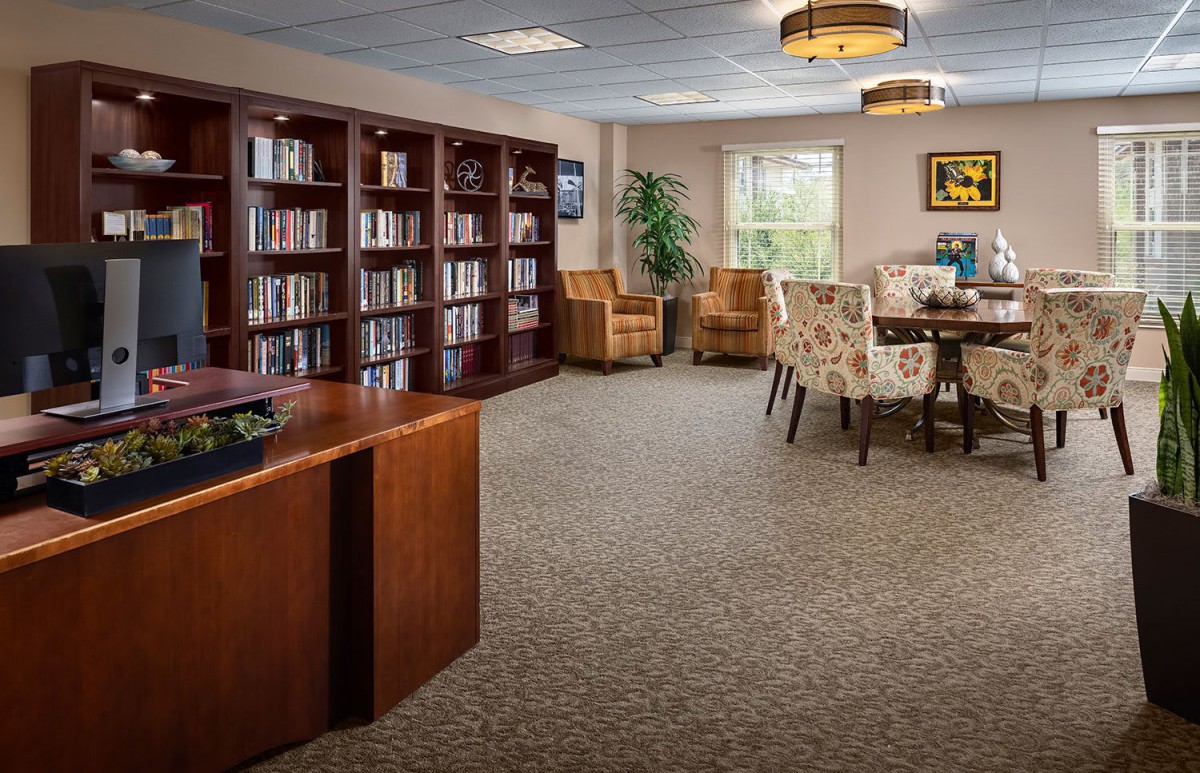 A cozy library room with bookshelves, comfortable chairs, and a reading table.