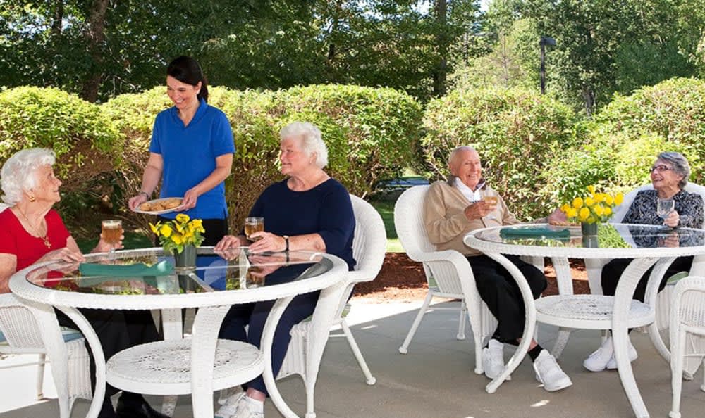 A group of seniors enjoying a relaxing day outdoors on a patio with a nurse assisting them.