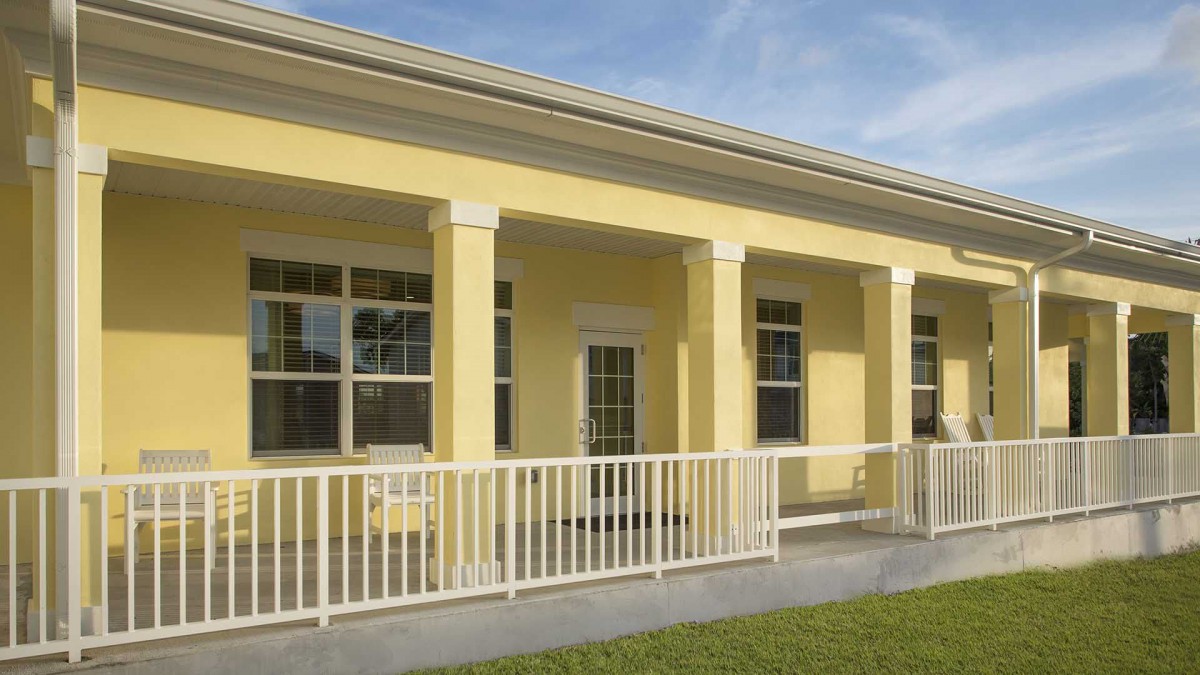 A yellow house with a porch and columns.