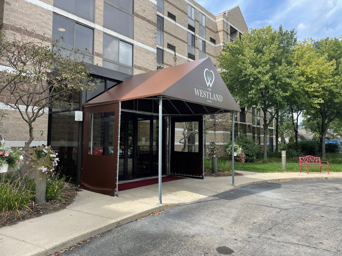 The entrance to a hotel with an awning over the sidewalk.