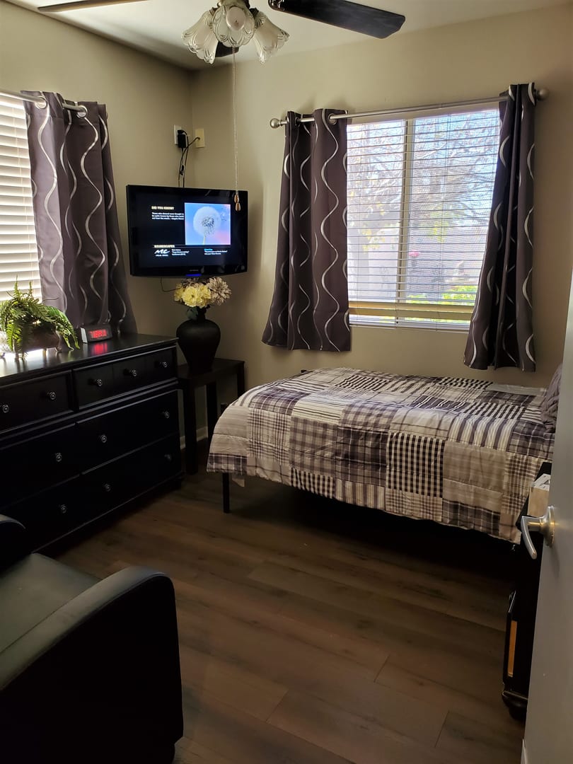 Cozy bedroom with a single bed, TV, and dresser.