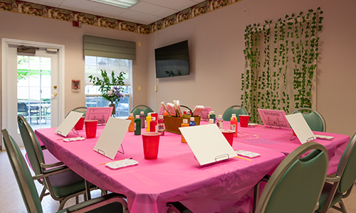A painting class setup with easels and art supplies on a pink-covered table, ready for participants.