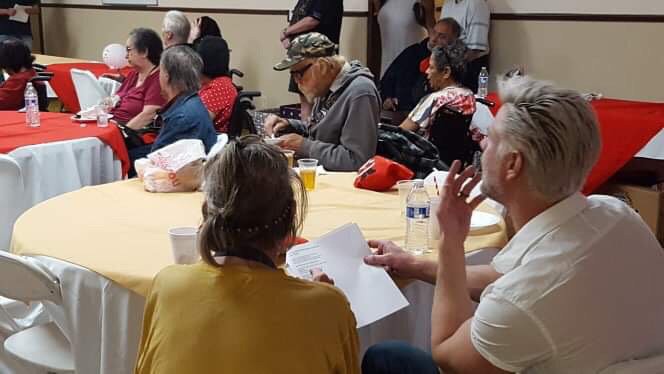 A group of people sitting around tables at a community event.