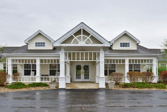 A front view of a large residential building with white columns and a triangular roof design.