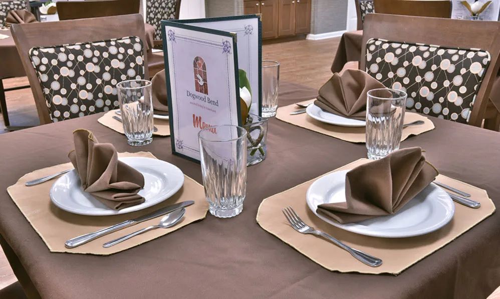 A neatly arranged restaurant table with brown napkins and glassware.